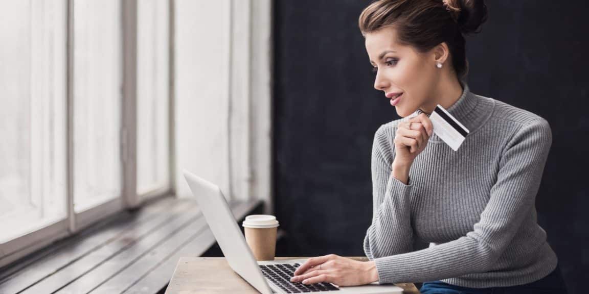 mulher empreendedora olhando para o computador com um cartão de crédito na mão